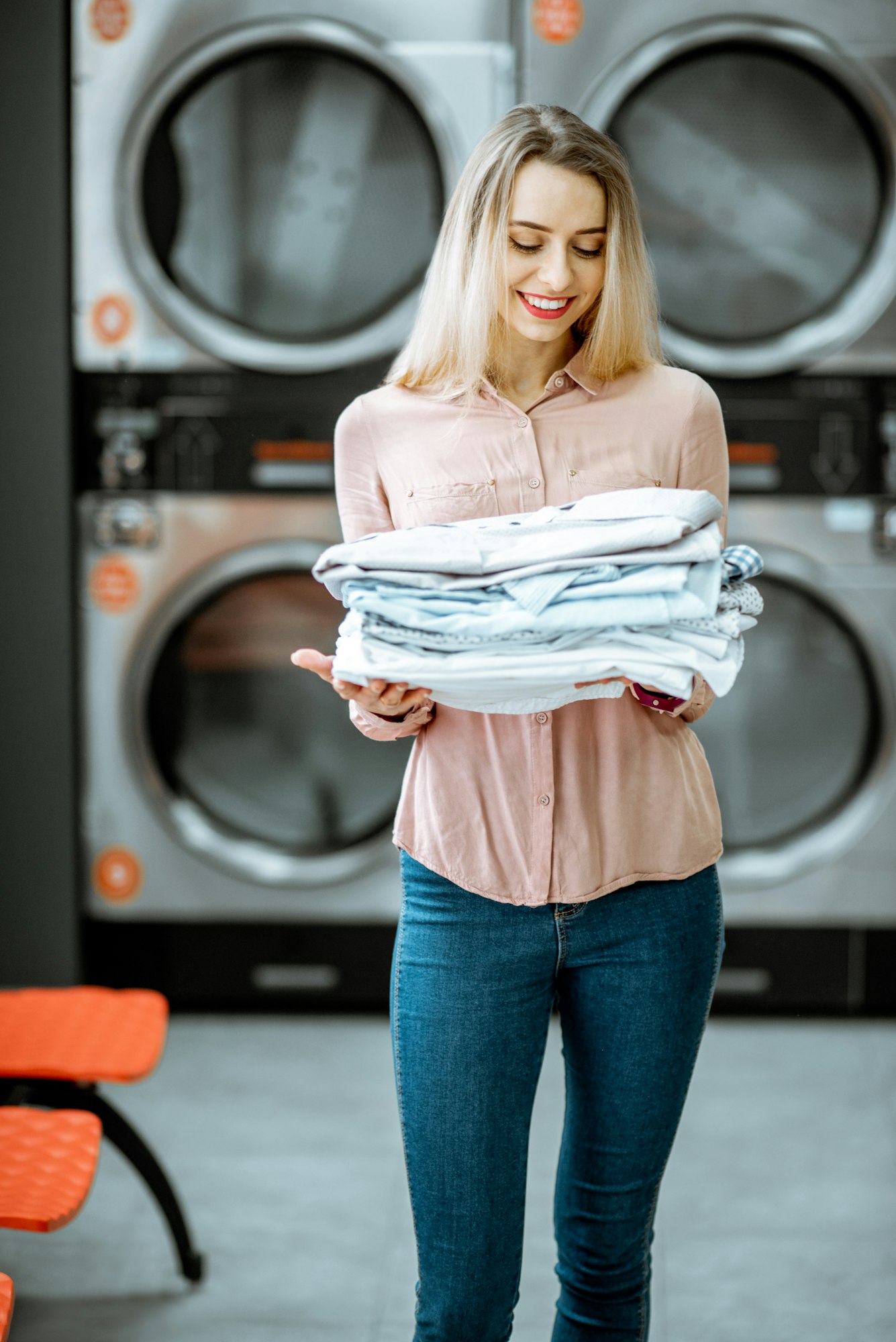 Woman with ironed clothes in the laundry